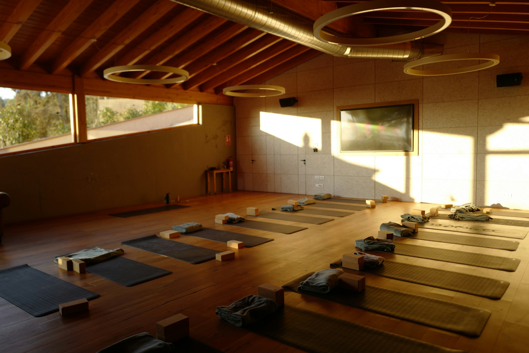 Sala de yoga cu lemn cald, ferestre și saltele pregătite