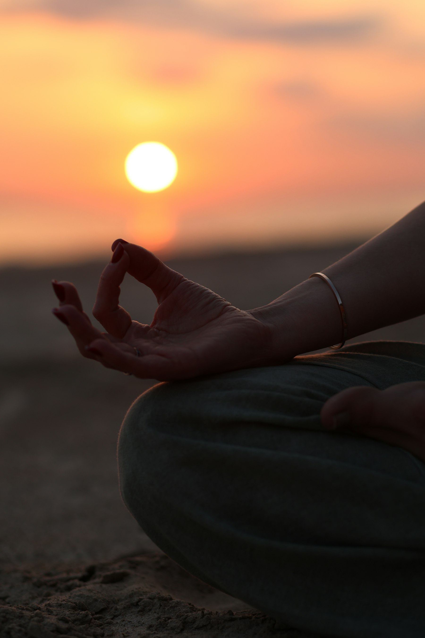 Mână în mudra, în meditație, cu soarele la apus în fundal